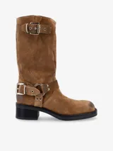 Bota de caña media de cuero negro, estilo biker, con caña arrugada y detalles de correas con hebillas metálicas plateadas en la parte superior y alrededor del tobillo. Posee un taco bajo y grueso.