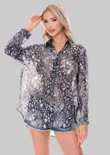 Camisa de mangas largas confeccionada en tela transparente con estampado abstracto en tonos grises y detalles de brillos dorados.