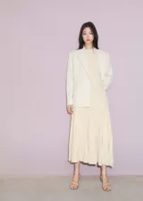 Vestido largo color durazno, de tejido de punto fino con diseño plisado y evasé. Sin mangas y con cuello halter.