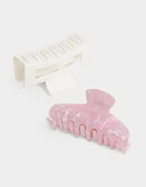 Set de dos broches para el pelo, uno con acabado de resina rosa y blanco, y otro de plástico blanco con forma geométrica.