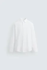 Camisa blanca de algodón, corte regular fit, cuello italiano, manga larga con puños abotonados y cierre frontal con botones.