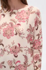 Sweater de tejido de punto, color crema, con estampado floral en tonos rosados y marrones. Presenta cuello redondo y mangas largas.