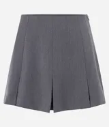 Short pollera gris de corte sastrero con pliegues anchos delanteros y traseros, y cierre invisible lateral.