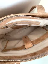 Cartera tipo tote de cuero graneado color negro, con textura uniforme y suave al tacto. Tiene manijas de 55 cm, bolsillo frontal con broche imantado, bolsillo trasero con cierre metálico, cierre principal metálico, forro interior y tres bolsillos internos (uno con cierre, uno plaqué y uno tipo sobre con solapa y botón).