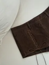 Short marrón de gamuza con cintura alta, corte ajustado y cordones cruzados en los laterales.