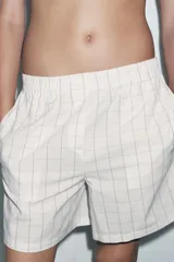 Shorts de algodón color gris claro con estampado de cuadros negros, tiro medio y cintura elástica.