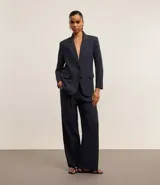 Pantalón de vestir azul marino, de corte wide leg, con cintura alta, bolsillos laterales y traseros. Se ajusta a la cintura con cinturón de cuero marrón.