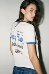 Camiseta blanca de algodón con cuello redondo y mangas cortas con ribete azul. Estampado frontal de Mickey Mouse y texto 'California'.