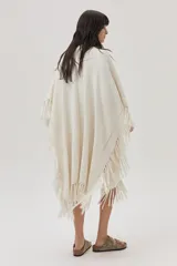Ruana tejida color crema con flecos y lurex dorado.