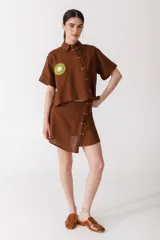 Minifalda color ladrillo con rayas verticales finas y botones dorados en el lateral.