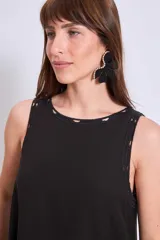 Vestido negro de corte holgado y largo a la rodilla, con cuello redondo y sin mangas. Presenta bordados florales en el escote y bolsillos laterales.