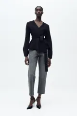 Pantalón de jean gris oscuro, de corte mom fit, tiro alto y largo tobillero. Cuenta con cinco bolsillos, cierre frontal con cremallera y botón.