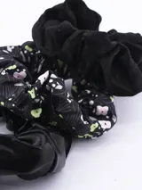Pack de tres coleros para el pelo, uno de terciopelo negro, uno de satén negro y uno estampado con flores y calaveras en blanco y verde sobre fondo negro.