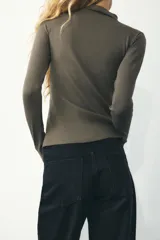 Camiseta blanca de manga larga con cuello alto y corte ajustado.