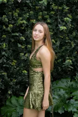 Vestido corto de lentejuelas color verde oliva, con escote en V, breteles finos cruzados en la espalda, cut-outs laterales y volado en el ruedo.