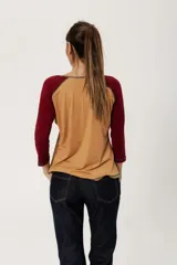 Remera color camel de algodón con mangas ranglan 3/4 color bordó y estampa de plumas en el frente.