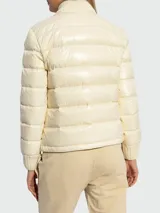 Campera puffer color crema con cuello alto de lana, cierre frontal con cremallera y bolsillos laterales con ribetes de lana.