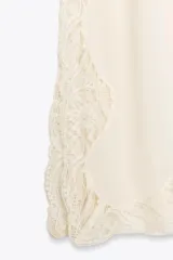 Top color crema con tirantes finos y escote redondo. Detalles de encaje en el escote y en el ruedo.