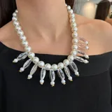 Collar de perlas plásticas blancas con detalles de resina transparente y herrajes dorados.