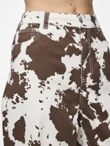 Pantalón de jean ancho con estampado de cebra en tonos marrones y blancos.