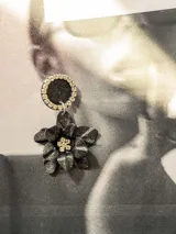 Par de aros colgantes con base circular negra con borde de strass y dije de flor negra con centro de strass.