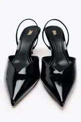 Zapato destalonado de charol negro con escote en pico, tira trasera ajustable y tacón fino.