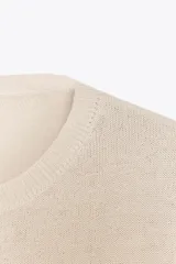 Jersey color crema de punto liso con cuello redondo y manga larga, confeccionado con lana.
