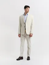 Saco de lino color beige, de corte clásico, con solapas de muesca, cierre de dos botones y bolsillos de parche.