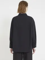 Camisa negra de corte amplio con botones en la parte delantera y aplique de macramé en el frente.