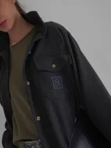 Camisa gris de lana con corte clásico, cuello camisero, cierre frontal con botones de cuerno y dos bolsillos de parche en el pecho.