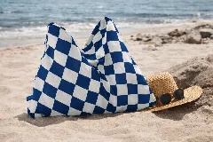 Toalla de playa con estampado a cuadros azules y blancos que se transforma en un bolso tipo saco.