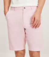 Bermuda de hombre en lino color gris claro, de corte recto, con textura discreta, bolsillos laterales y cierre frontal con botón y cremallera.