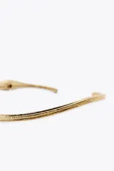 Gargantilla choker rígida de metal dorado con textura acanalada.