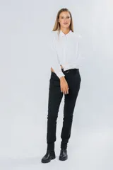 Pantalón de gabardina gris oscuro, corte skinny, con bolsillos delanteros y traseros. Se ajusta a la cintura con cinturón de cuero marrón con hebilla dorada.