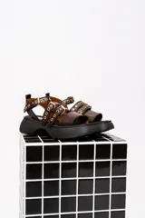 Sandalias de cuero color marrón con plataforma negra y hebillas metálicas.