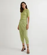 Pantalón jogger verde claro de tejido Orly (malla), con cintura elastizada, pliegues y amarre frontal con cuentas de madera.