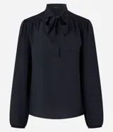 Blusa negra de crepé con cuello con lazo, mangas largas y pliegues en los hombros.