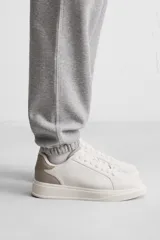 Zapatillas deportivas blancas con detalle en color gris en el talón y suela con plataforma.