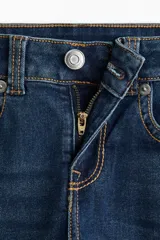 Jean de tiro bajo con corte acampanado desde la rodilla. Confeccionado en denim con leve stretch, presenta bolsillos delanteros abiertos y bolsillos traseros con solapa y botón.