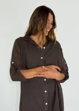 Vestido camisero largo color beige, con cuello clásico, abotonadura frontal completa, mangas 3/4 con trabilla y aberturas laterales.