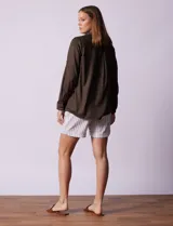 Camisa blanca de lyocell marca Cyrus, con cuello con solapa, abertura central con botones, mangas largas regulables con presilla y botón, y bolsillos delanteros aplicados.
