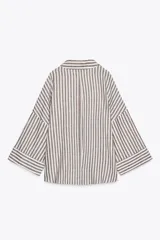 Camisa a rayas verticales color marrón y blanco, de corte holgado, con cuello solapa, cierre frontal con botones y mangas anchas por debajo del codo.