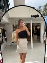 Pollera corta negra de ecocuero, con cortes y detalles de bolsillos grandes.