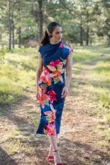 Vestido midi azul marino con estampado de flores rojas, naranjas y rosas. Tiene cuello drapeado y corte ajustado al cuerpo.