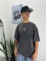 Remera gris oscuro con efecto lavado, corte oversize y estampado pequeño de una cruz en el centro del pecho.