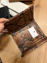 Billetera de cuero marrón con estampado de piel de serpiente, con cierre de broche a presión.