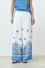 Pantalón blanco con estampado floral y guarda geométrica en tonos de azul.