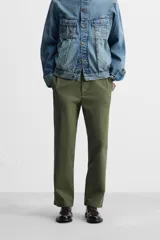Pantalón chino color verde militar, de corte recto, con bolsillos laterales y traseros de vivo. Cierre frontal con cremallera y botón.