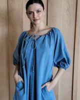 Vestido midi celeste de denim, con escote con lazo, mangas 3/4 abullonadas y corte evasé.