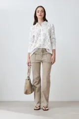 Camisa blanca de broderie con cuello clásico, cierre frontal con botones y mangas largas.